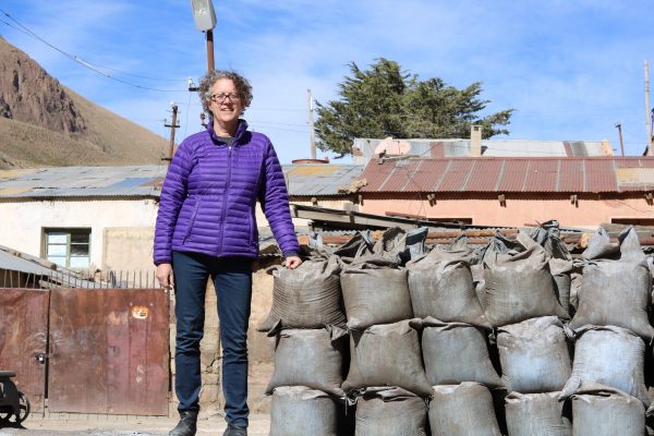 Dr. Mary Van Buren, standing next to bags of mineral ore in highland Bolivia, where she conducts research and studies indigenous and small-scale mining history and current practices