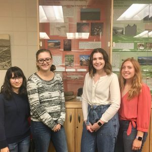 Anthropology and Geography students (left to right) Morgan Wilson, Jessie McCaig, Karlie Dorland, and Kit Kelly in front of the exhibition they designed in ANTH 462