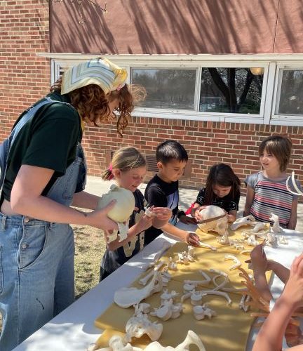 Undergraduate and Anthropology Club president Kalila Garrison shows Dunn Elementary first graders casts of human skeletal bones