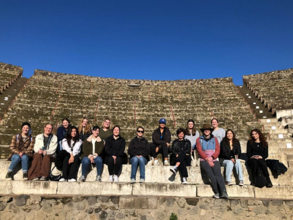 Class group sitting on stone steps of an ancient Roman coliseum in Italy