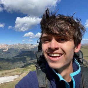 Closeup of student with mountains and blue sky in background