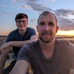 Two people standing outside with sunset behind them