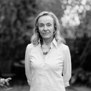 Portrait of a woman in a white shirt standing in front of trees.