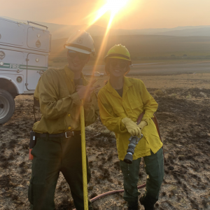 Two fire crew members standing in front of truck and sunset