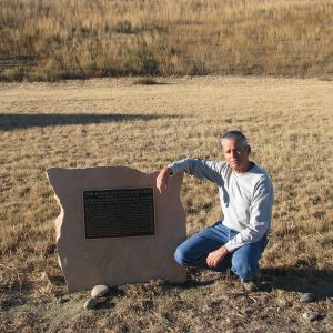 Professor squatting next to historical marker