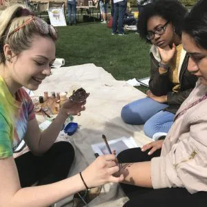 Woman paints another woman's arm for Prehistoric Technology Day