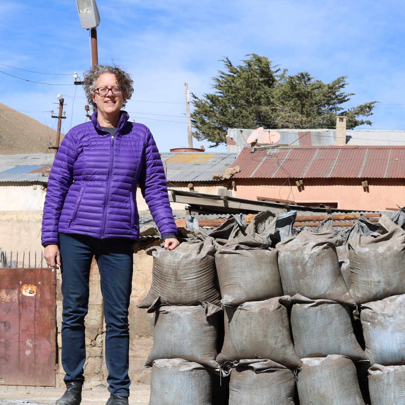 Mary Van Buren, standing next to bags of mineral ore in highland Bolivia