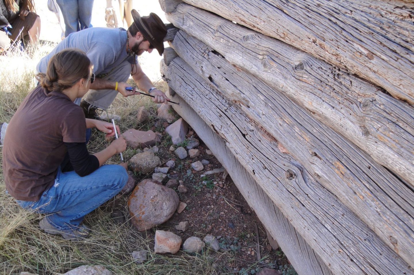 Student and professor taking wood core samples from cabin building