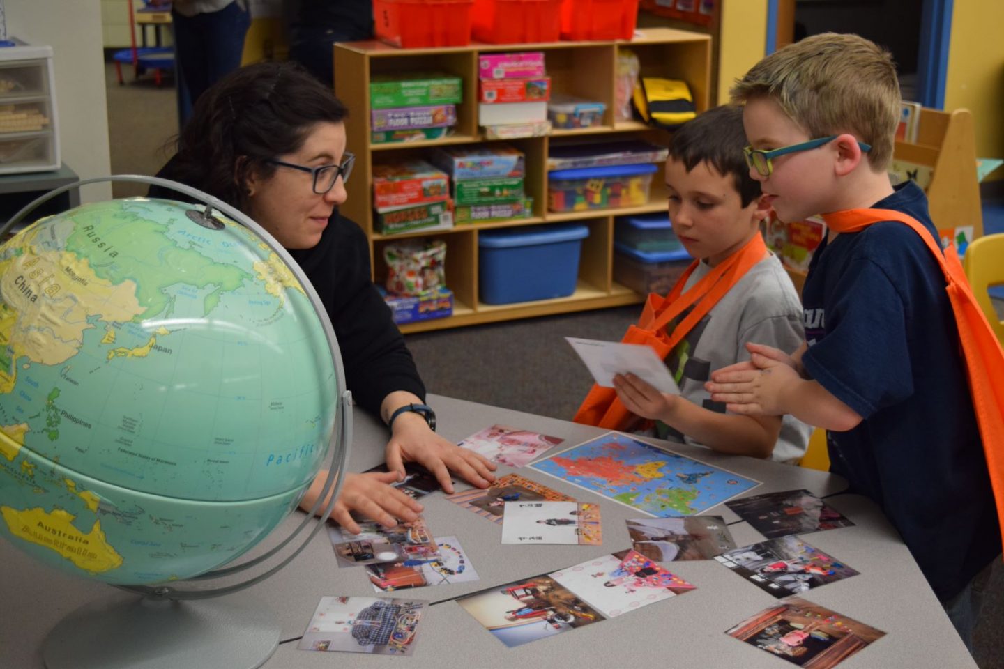 Woman talking with young kids about Geography with a globe