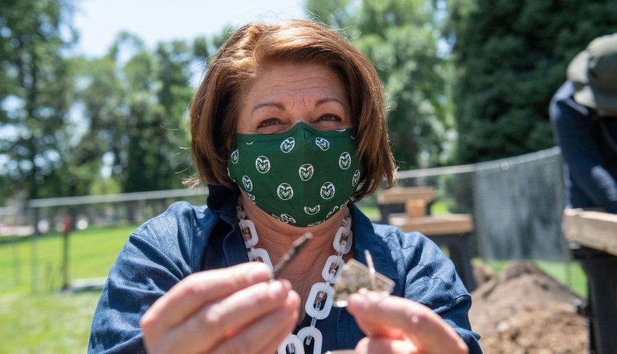 Photo of CSU president wearing mask and holding artifacts found at field school