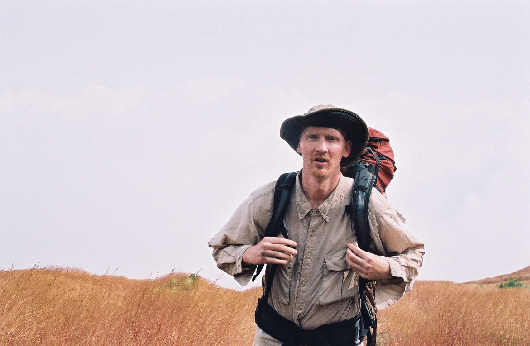 Photo of professor wearing backpack with field in background