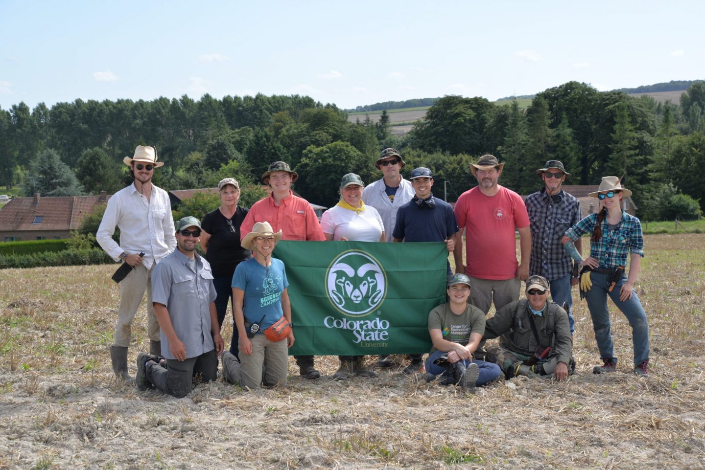 Group photo of people on military recovery archaeology mission with colorado state university flag