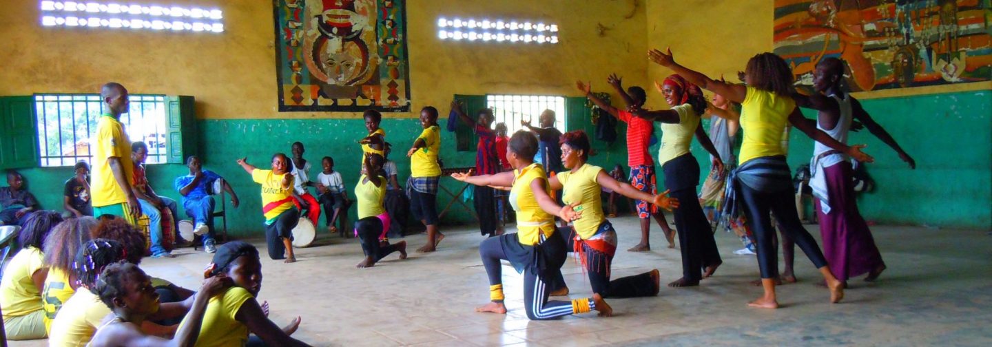 Photo of dance troupe in yellow shirts practicing indoors