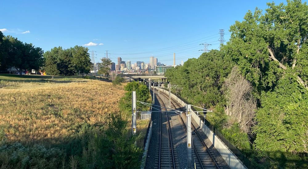 Denver Skyline during daytime with railroad tracks leading towrd cityscape in foreground