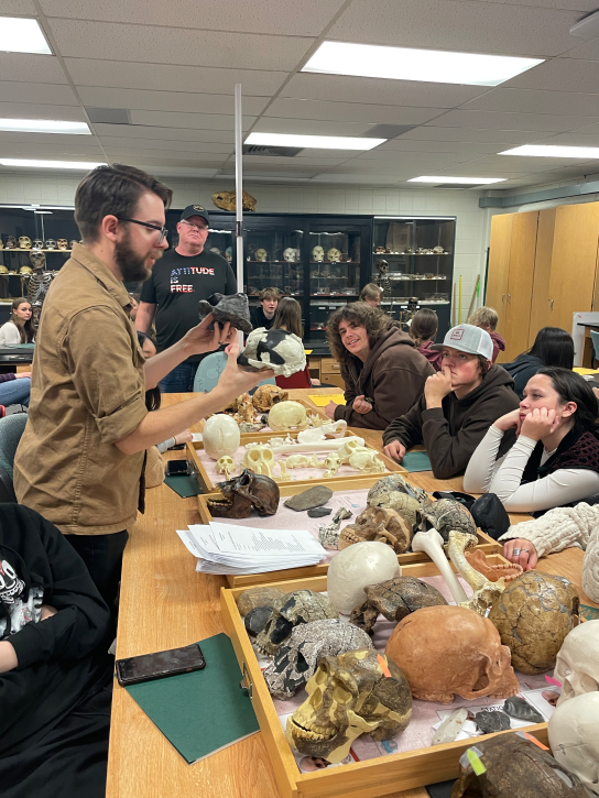 Instructor in Bone Lab asks students to compare skull casts standing at a table with other primate skull casts