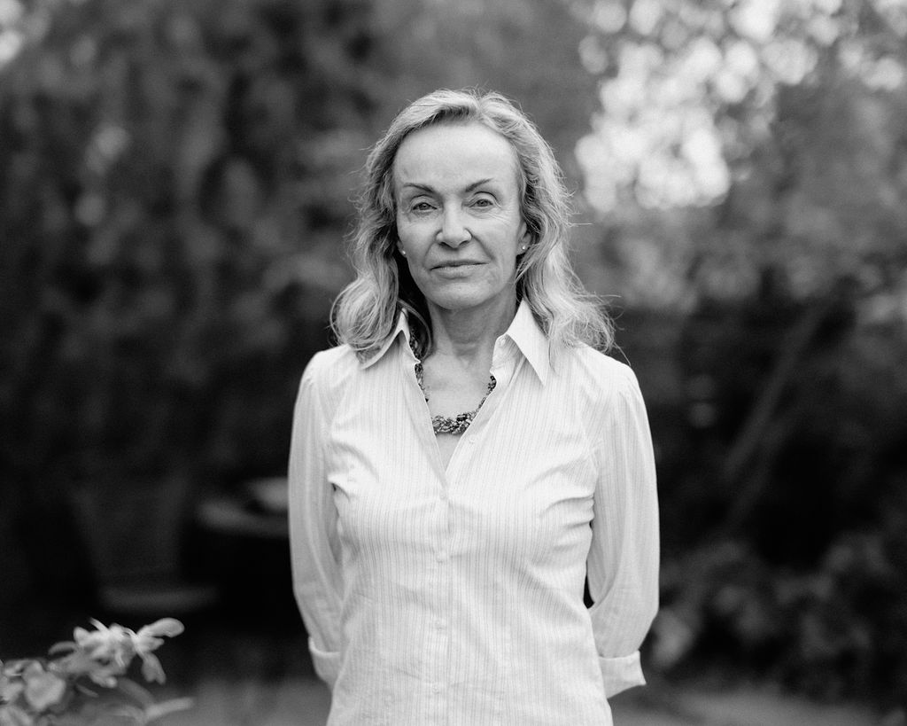 Portrait of a woman in a white shirt standing in front of trees.
