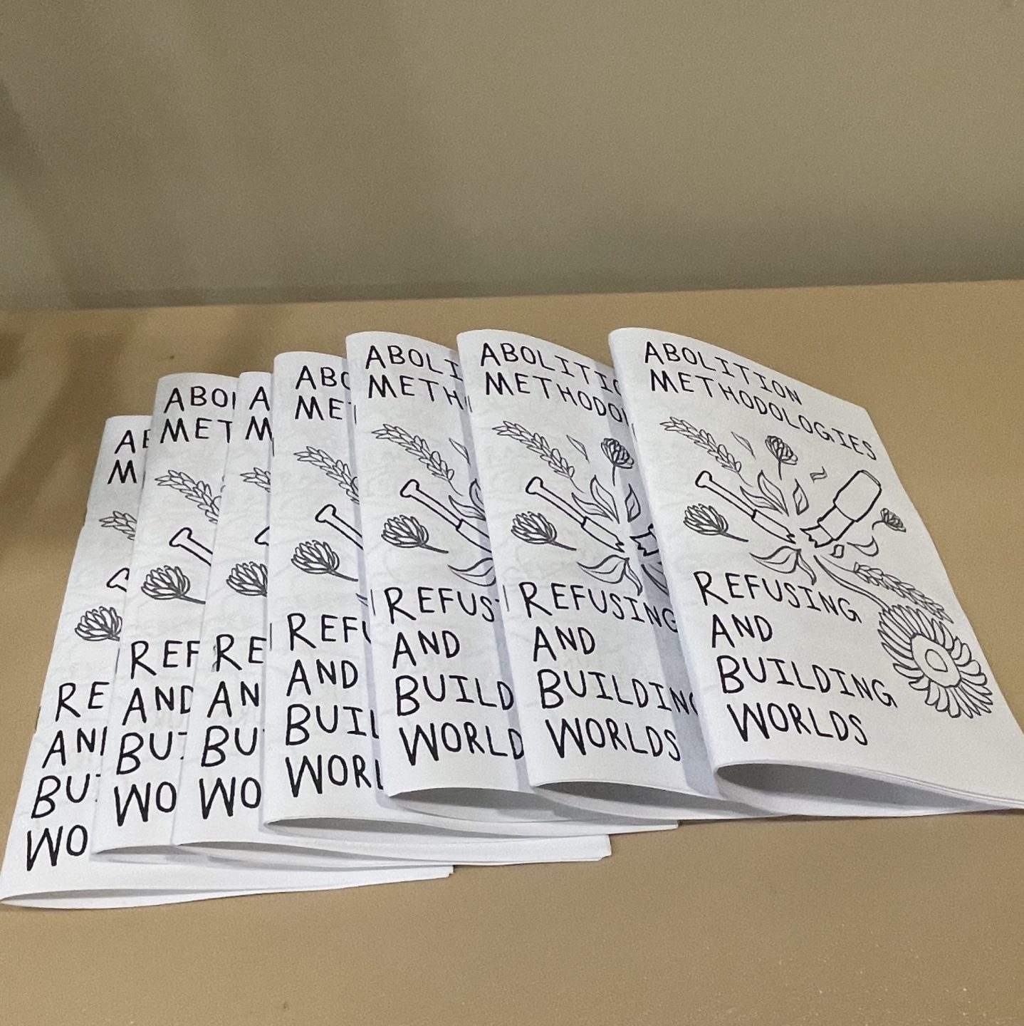 Display of paper zines on table. Zine cover reads Abolition Methodologies Refusing and Building Worlds