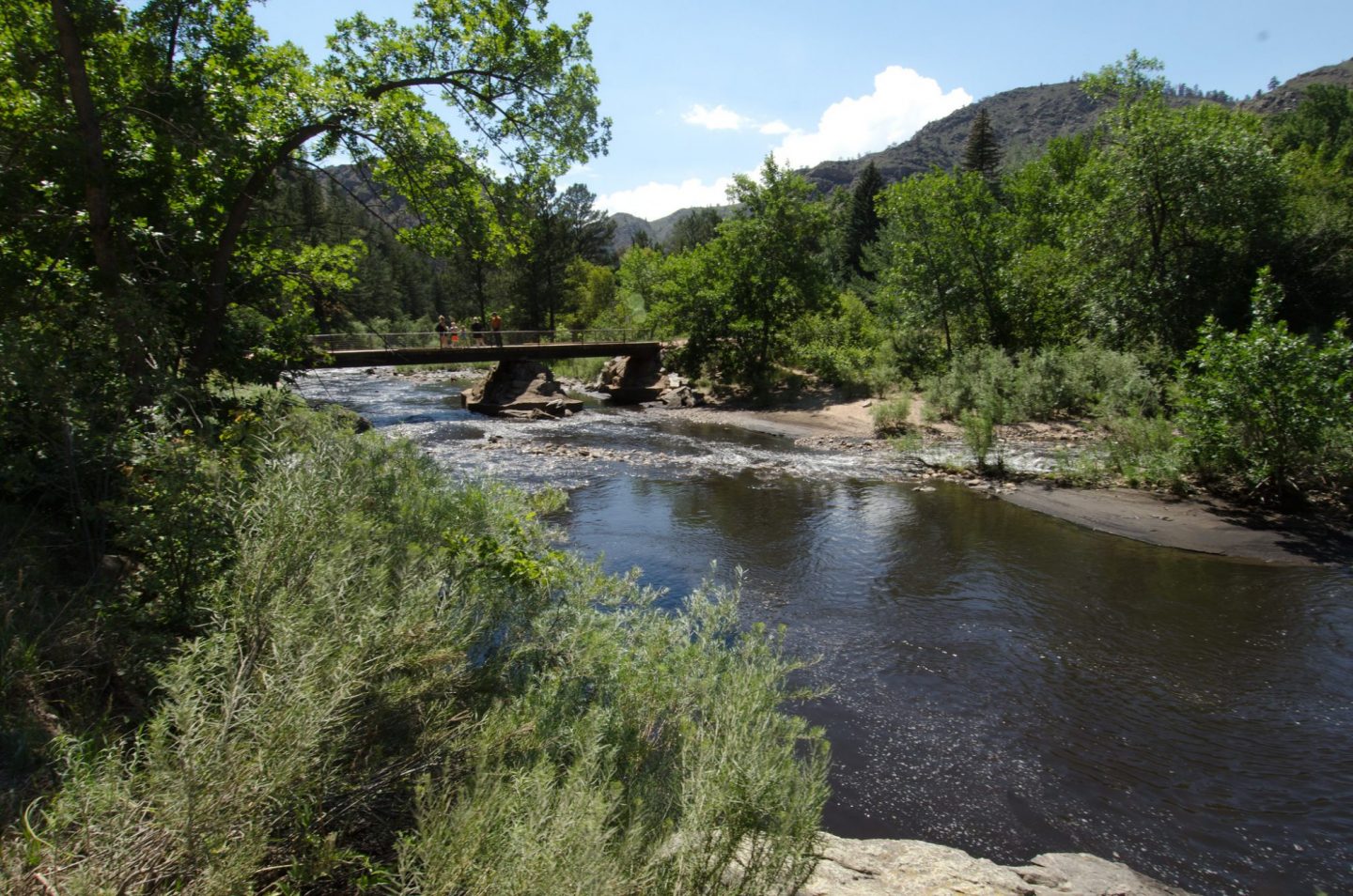 Photo of the Poudre River with a USDA employee speaking with a family on a bridge